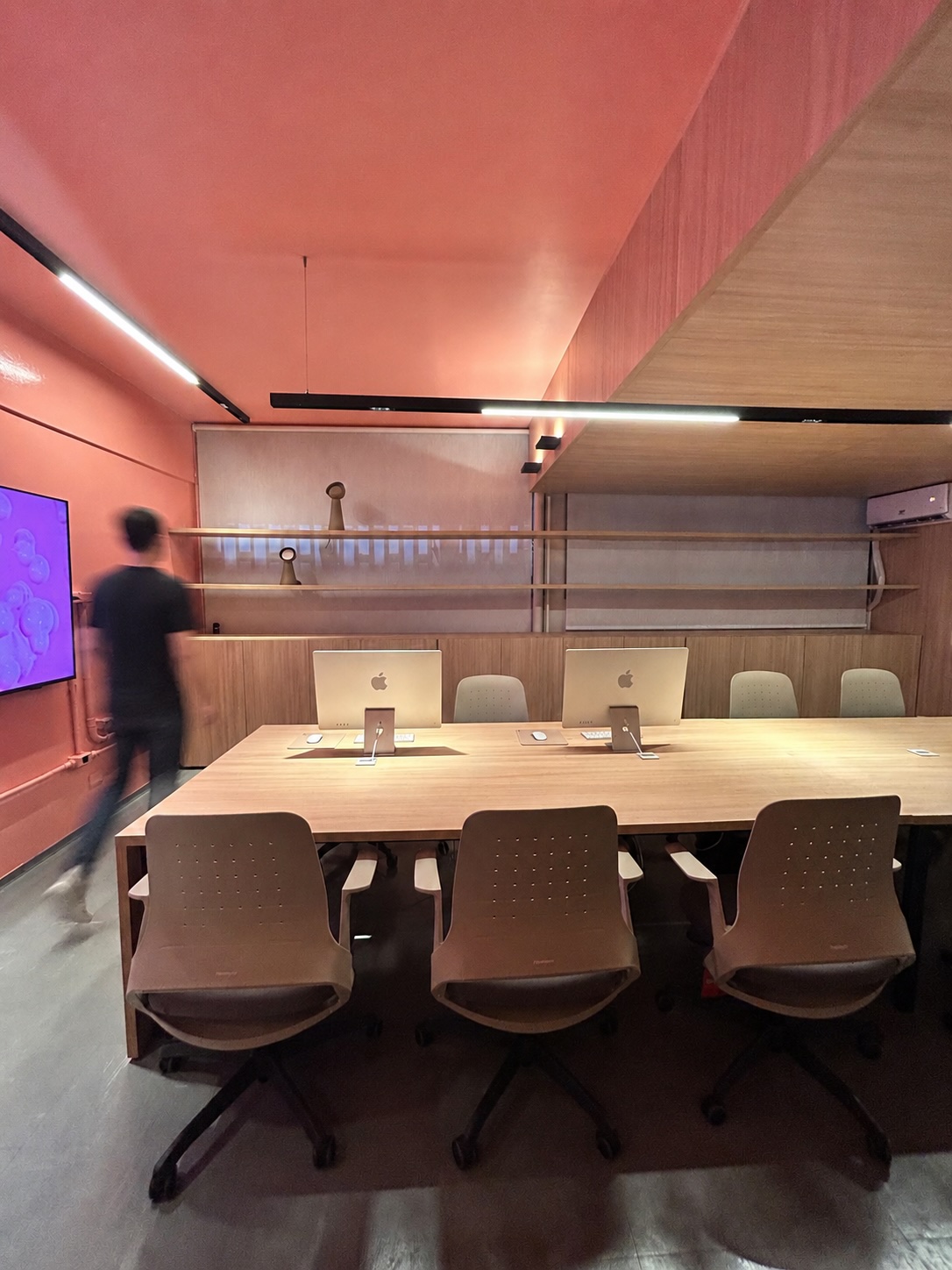 Pessoa em movimento no laboratório do NDS, entre computadores e espaço de projeto
